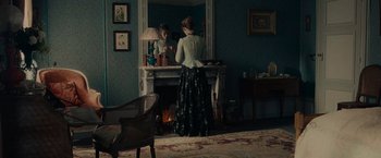 Movie still from “The Mad Women's Ball” (2021), directed by Mélanie Laurent – A woman standing in front of a fireplace looking in a mirror; Wide shot, Over the shoulder angle
