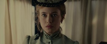 Movie still from “The Mad Women's Ball” (2021), directed by Mélanie Laurent – A young woman wearing a hat with a feather on it; Close Up shot, Low angle