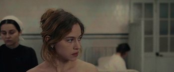 Movie still from “The Mad Women's Ball” (2021), directed by Mélanie Laurent – A young woman sitting in front of a man in a room; Close Up shot, Over the shoulder angle