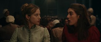 Movie still from “The Mad Women's Ball” (2021), directed by Mélanie Laurent – Two women are standing next to each other in front of a crowd of people; Close Up shot, Over the shoulder angle