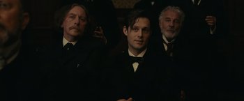 Movie still from “The Mad Women's Ball” (2021), directed by Mélanie Laurent – A group of men standing next to each other in a room; Medium shot, Over the shoulder angle