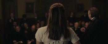 Movie still from “The Mad Women's Ball” (2021), directed by Mélanie Laurent – A woman standing in front of a crowd of people; Close Up shot, Over the shoulder angle