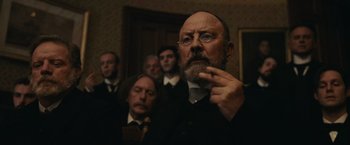 Movie still from “The Mad Women's Ball” (2021), directed by Mélanie Laurent – A group of men standing in a room; Close Up shot, Low angle