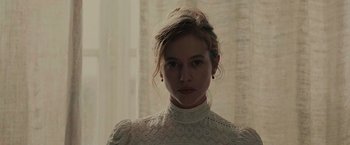 Movie still from “The Mad Women's Ball” (2021), directed by Mélanie Laurent – A woman in a white dress standing in front of a window; Close Up shot, Low angle