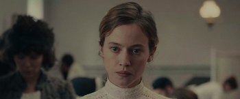Movie still from “The Mad Women's Ball” (2021), directed by Mélanie Laurent – A young woman in a white shirt is looking at the camera; Close Up shot, Over the shoulder angle
