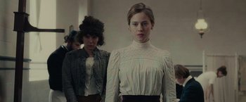 Movie still from “The Mad Women's Ball” (2021), directed by Mélanie Laurent – A woman in a white blouse standing next to another woman in a white blouse; Medium shot, Low angle