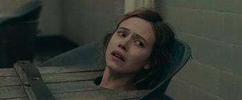 Movie still from “The Mad Women's Ball” (2021), directed by Mélanie Laurent – A young woman sitting in a chair with her eyes wide open; Close Up shot, Over the shoulder angle