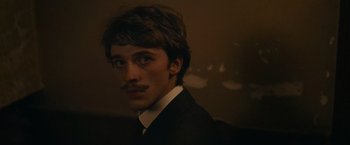 Movie still from “The Mad Women's Ball” (2021), directed by Mélanie Laurent – A man in a suit and tie with a mustache; Close Up shot, Over the shoulder angle