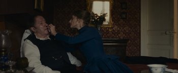 Movie still from “The Mad Women's Ball” (2021), directed by Mélanie Laurent – A woman in a blue dress is sitting at a table; Medium shot, Over the shoulder angle