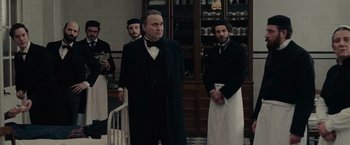 Movie still from “The Mad Women's Ball” (2021), directed by Mélanie Laurent – A group of men standing next to each other in a room; Medium shot, Low angle