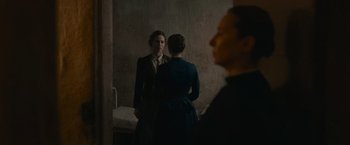 Movie still from “The Mad Women's Ball” (2021), directed by Mélanie Laurent – Two women are standing in front of a mirror; Medium shot, Over the shoulder angle