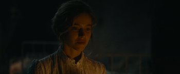 Movie still from “The Mad Women's Ball” (2021), directed by Mélanie Laurent – A woman in a white shirt is standing in the dark; Close Up shot, Over the shoulder angle