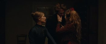 Movie still from “The Mad Women's Ball” (2021), directed by Mélanie Laurent – A group of people standing next to each other in a dark room; Medium shot, Over the shoulder angle