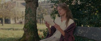 Movie still from “The Mad Women's Ball” (2021), directed by Mélanie Laurent – A woman sitting on a bench reading a piece of paper; Medium shot, Over the shoulder angle