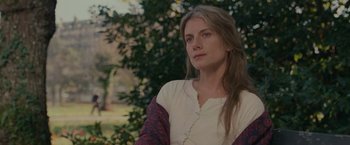 Movie still from “The Mad Women's Ball” (2021), directed by Mélanie Laurent – A woman with long hair sitting in front of a tree; Close Up shot, Over the shoulder angle