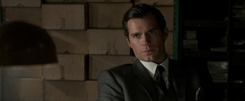 Movie still from “The Man from U.N.C.L.E.” (2015), directed by Guy Ritchie – A man wearing a suit and tie in front of boxes; Close Up shot, Over the shoulder angle