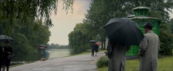 Movie still from “The Man from U.N.C.L.E.” (2015), directed by Guy Ritchie – Two people walking down a sidewalk holding umbrellas; Extreme Wide shot, High angle