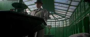 Movie still from “The Man from U.N.C.L.E.” (2015), directed by Guy Ritchie – A man wearing a hat and a trench coat; Medium shot, Low angle