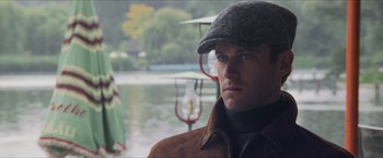 Movie still from “The Man from U.N.C.L.E.” (2015), directed by Guy Ritchie – A person wearing a hat near a body of water; Close Up shot, Over the shoulder angle