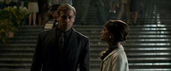 Movie still from “The Man from U.N.C.L.E.” (2015), directed by Guy Ritchie – A man and a woman standing next to each other in front of stairs; Medium shot, Over the shoulder angle