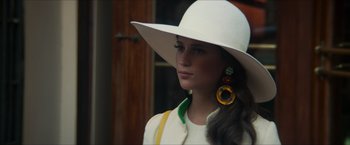Movie still from “The Man from U.N.C.L.E.” (2015), directed by Guy Ritchie – A woman wearing a white hat and yellow earrings; Close Up shot, Over the shoulder angle