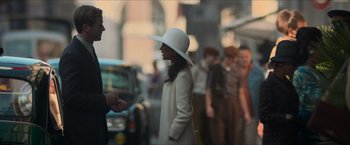 Movie still from “The Man from U.N.C.L.E.” (2015), directed by Guy Ritchie – A woman wearing a white hat talking to a man in a crowd; Medium shot, Over the shoulder angle