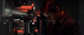 Movie still from “The Man from U.N.C.L.E.” (2015), directed by Guy Ritchie – A young man looking at a camera in a dark room; Close Up shot, Low angle