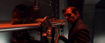 Movie still from “The Man from U.N.C.L.E.” (2015), directed by Guy Ritchie – A man standing in front of a machine; Medium shot, Over the shoulder angle