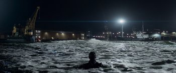Movie still from “The Man from U.N.C.L.E.” (2015), directed by Guy Ritchie – A man in a wetsuit swimming in a body of water at night; Extreme Wide shot, Over the shoulder angle