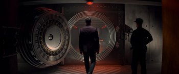 Movie still from “The Man from U.N.C.L.E.” (2015), directed by Guy Ritchie – A man in a suit walking in front of an open door; Wide shot, Low angle