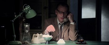 Movie still from “The Man from U.N.C.L.E.” (2015), directed by Guy Ritchie – An older man sitting at a table talking on the phone; Medium shot, Low angle