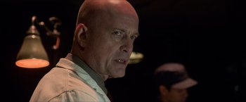 Movie still from “The Man from U.N.C.L.E.” (2015), directed by Guy Ritchie – A man with a bald head looking into the camera; Close Up shot, Over the shoulder angle