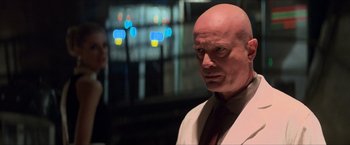 Movie still from “The Man from U.N.C.L.E.” (2015), directed by Guy Ritchie – A man with a bald head wearing a suit and tie; Close Up shot, Over the shoulder angle