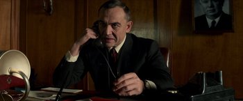 Movie still from “The Man from U.N.C.L.E.” (2015), directed by Guy Ritchie – A man in a suit and tie talking on a phone; Medium shot, Low angle