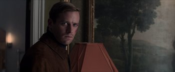 Movie still from “The Man from U.N.C.L.E.” (2015), directed by Guy Ritchie – A man standing in front of a lamp in front of a painting; Close Up shot, Low angle