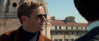 Movie still from “The Man from U.N.C.L.E.” (2015), directed by Guy Ritchie – A person wearing a jacket and sunglasses; Close Up shot, Over the shoulder angle