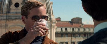 Movie still from “The Man from U.N.C.L.E.” (2015), directed by Guy Ritchie – A man drinking a glass of beer outside; Close Up shot, Over the shoulder angle