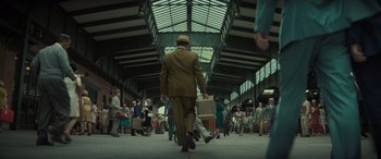 Movie still from “The Many Saints of Newark” (2021), directed by Alan Taylor – A group of people walking through a train station carrying suitcases; Wide shot, Low angle