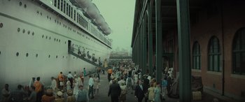Movie still from “The Many Saints of Newark” (2021), directed by Alan Taylor – A crowd of people walking on a sidewalk near a large ship; Extreme Wide shot, High angle