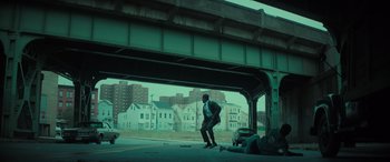 Movie still from “The Many Saints of Newark” (2021), directed by Alan Taylor – A man standing on the side of a road under an overpass; Extreme Wide shot, Low angle