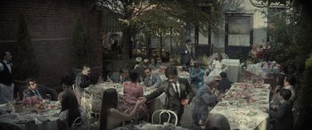 Movie still from “The Many Saints of Newark” (2021), directed by Alan Taylor – A group of people sitting at a table with food; Wide shot, High angle