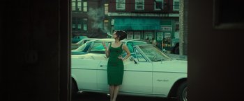 Movie still from “The Many Saints of Newark” (2021), directed by Alan Taylor – A woman standing next to a car on the side of the road; Wide shot, Low angle