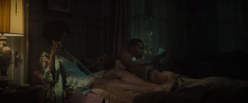 Movie still from “The Many Saints of Newark” (2021), directed by Alan Taylor – A man and a woman laying on a bed reading; Medium shot, Low angle
