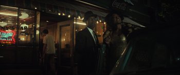 Movie still from “The Many Saints of Newark” (2021), directed by Alan Taylor – A man and a woman standing next to each other in front of a bar; Medium shot, Low angle