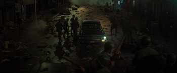 Movie still from “The Many Saints of Newark” (2021), directed by Alan Taylor – A group of soldiers standing around a car; Wide shot, High angle
