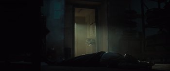 Movie still from “The Many Saints of Newark” (2021), directed by Alan Taylor – A person laying on a bed in a dark room next to an open door; Wide shot, Low angle