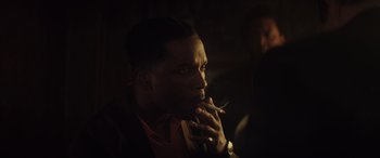 Movie still from “The Many Saints of Newark” (2021), directed by Alan Taylor – A man smoking a cigarette in a dark room; Close Up shot, Over the shoulder angle