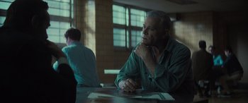 Movie still from “The Many Saints of Newark” (2021), directed by Alan Taylor – An older man sitting at a table with his hand under his chin; Medium shot, Over the shoulder angle