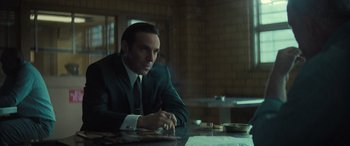 Movie still from “The Many Saints of Newark” (2021), directed by Alan Taylor – A man sitting at a table in front of a window; Medium shot, Over the shoulder angle