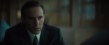 Movie still from “The Many Saints of Newark” (2021), directed by Alan Taylor – A man in a suit and tie sitting in a room; Close Up shot, Over the shoulder angle